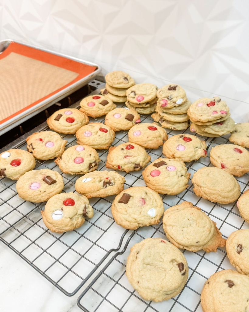 Freshly baked chocolate chip M&M cookies cooling on a wire rack.