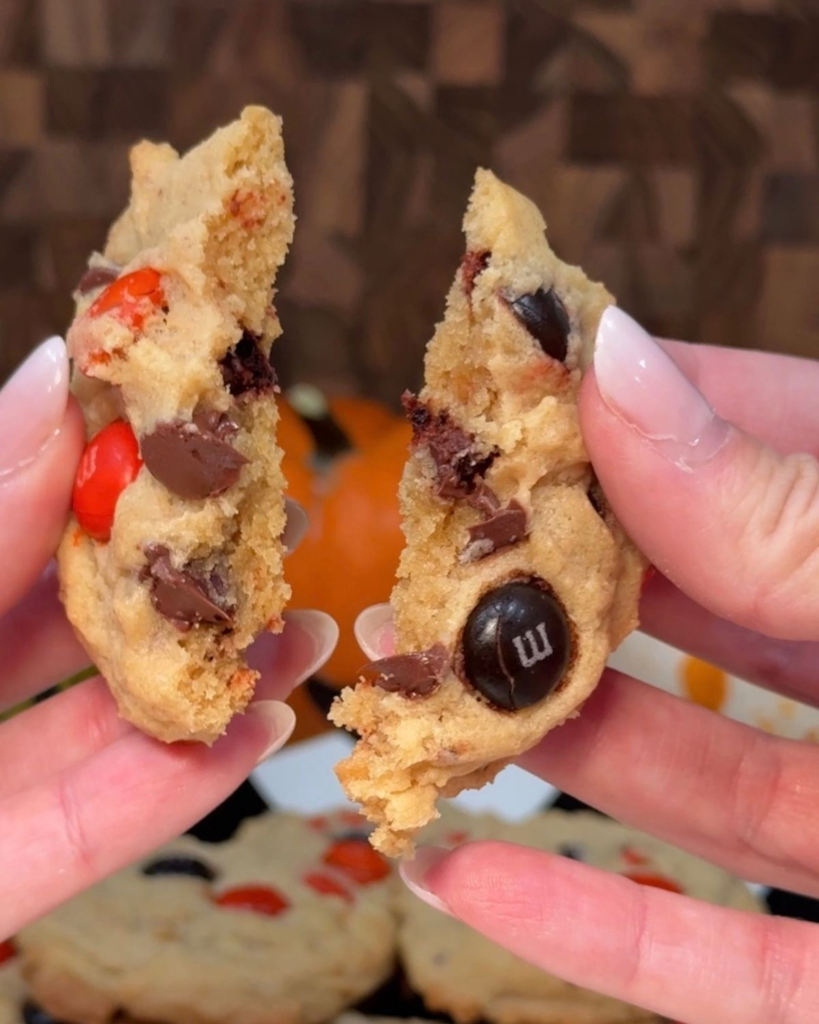 Chocolate chip M&M cookie broken in half to show the soft center and chocolate pieces.