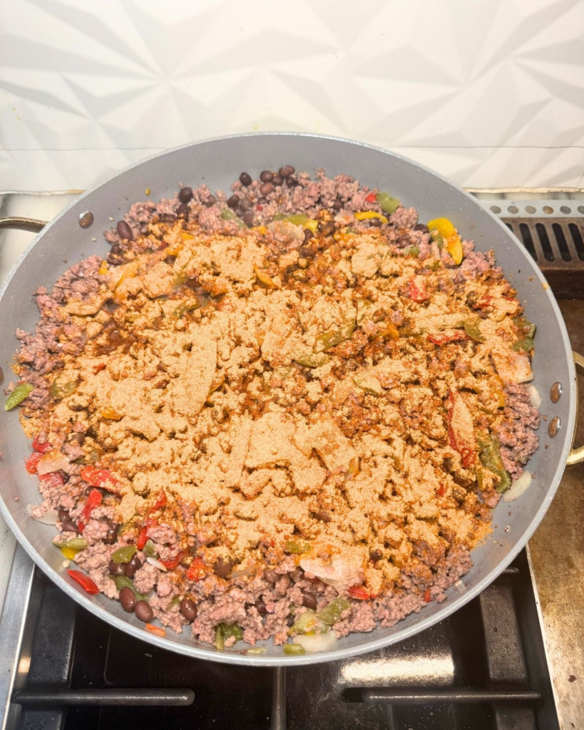Ground beef taco meat cooking in a skillet with seasoning
