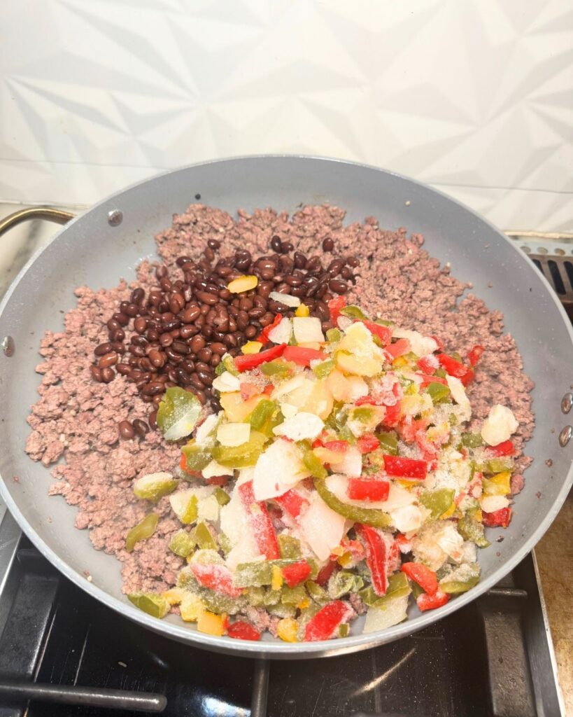 Ground beef taco mixture with black beans and colorful peppers in a skillet