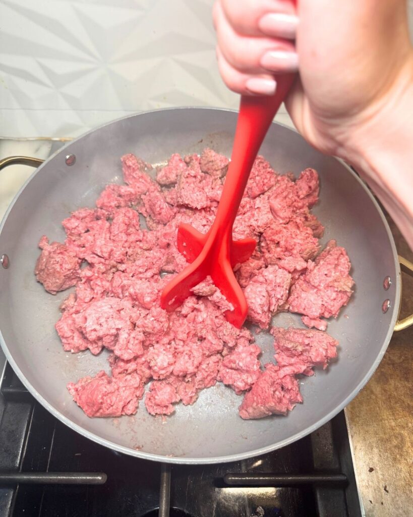 Ground beef being broken apart while cooking in a skillet