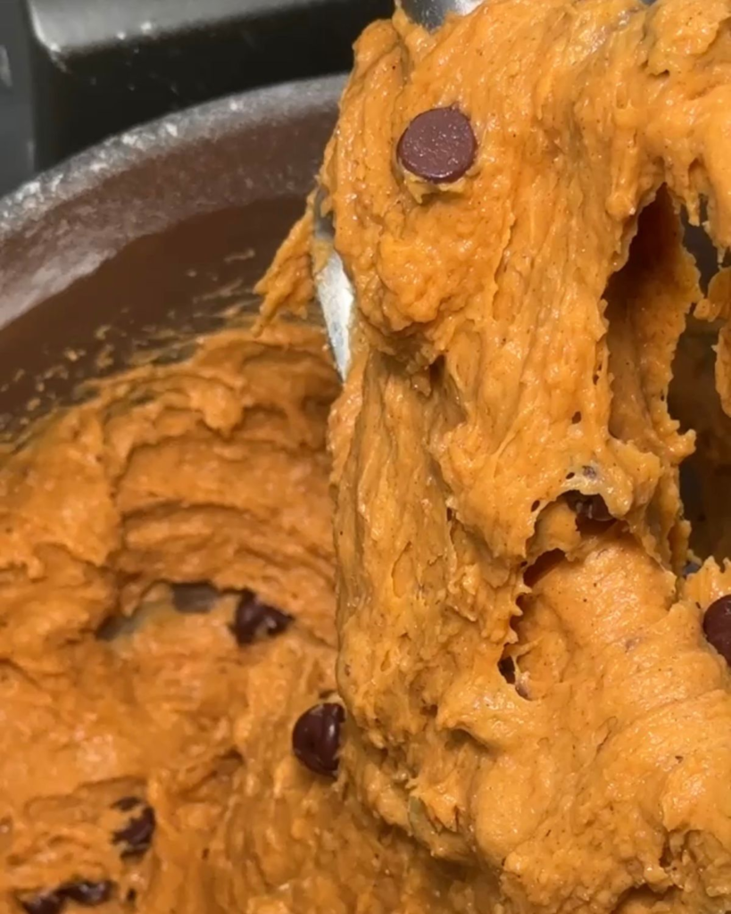 Pumpkin chocolate chip cookie dough mixed with chocolate chips in a stand mixer