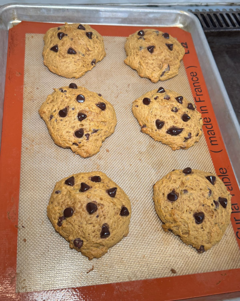 Large pumpkin chocolate chip cookies with chocolate chips baked on a silicone baking mat