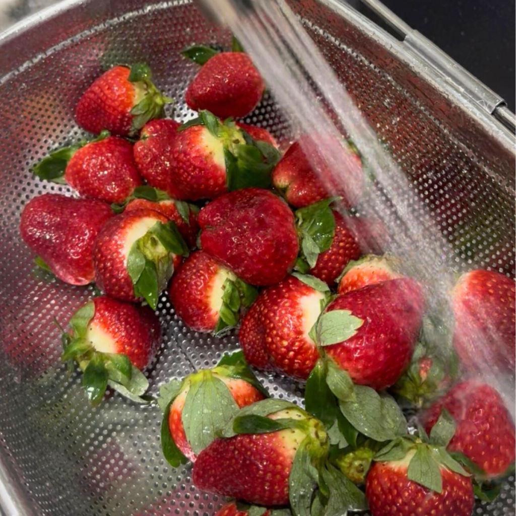 Washing fresh strawberries during weekly meal prep routine