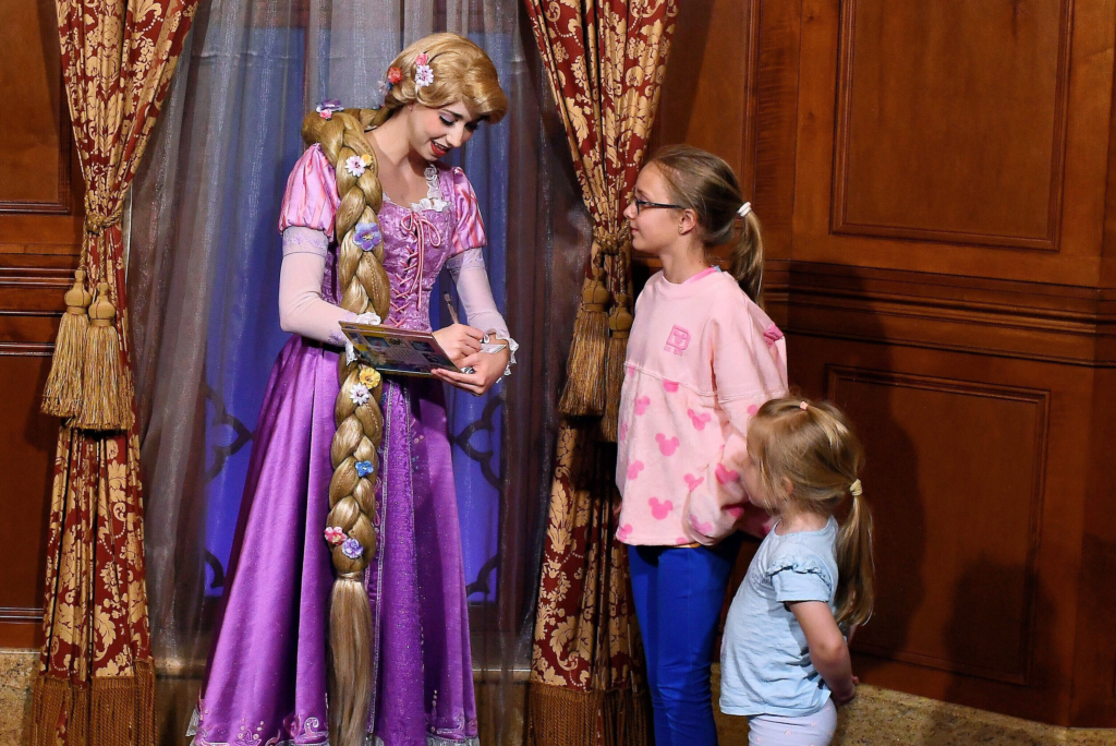 Rapunzel signing a child’s I am a Princess Golden Book during a character meet at Magic Kingdom