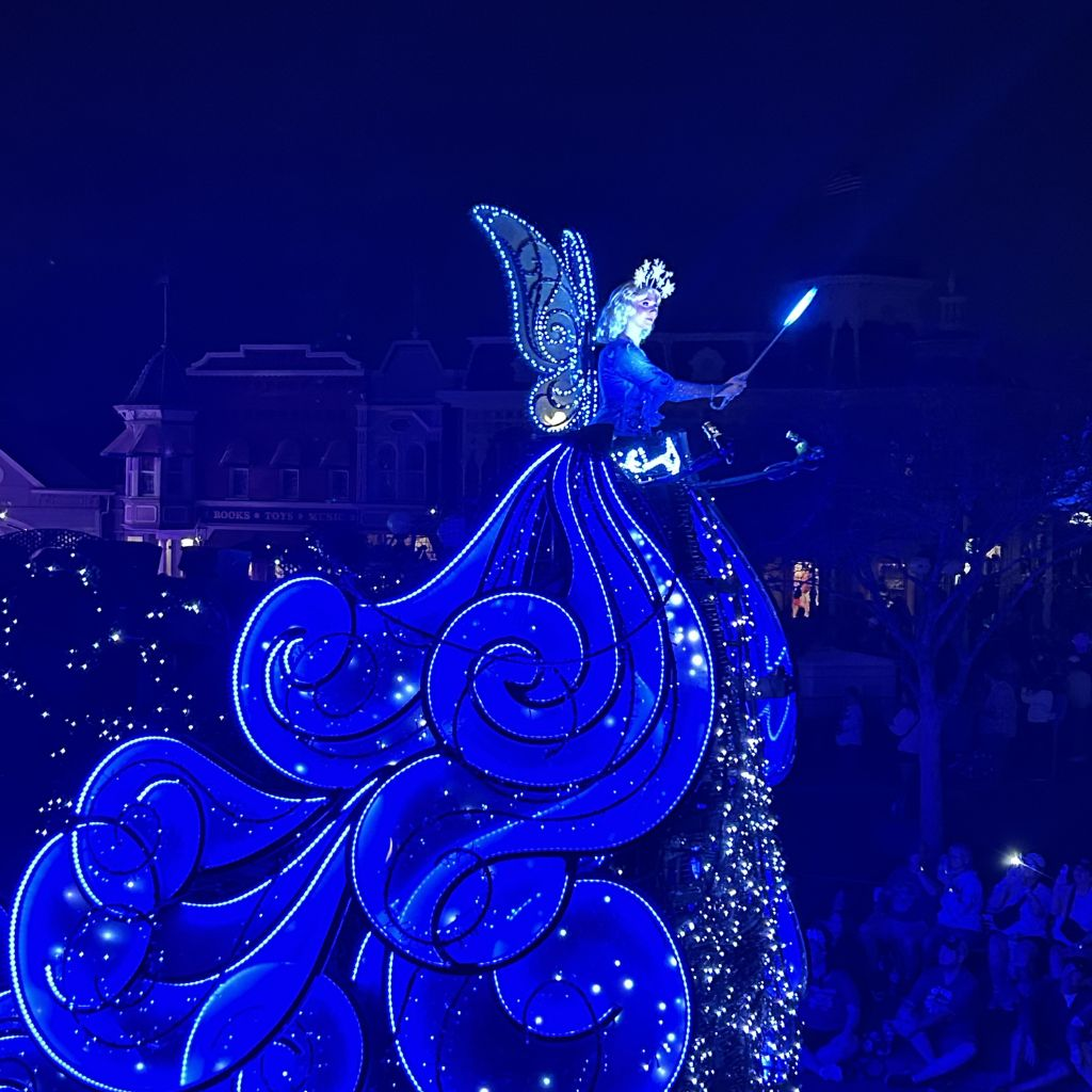 Blue Fairy glowing on nighttime parade float at Magic Kingdom