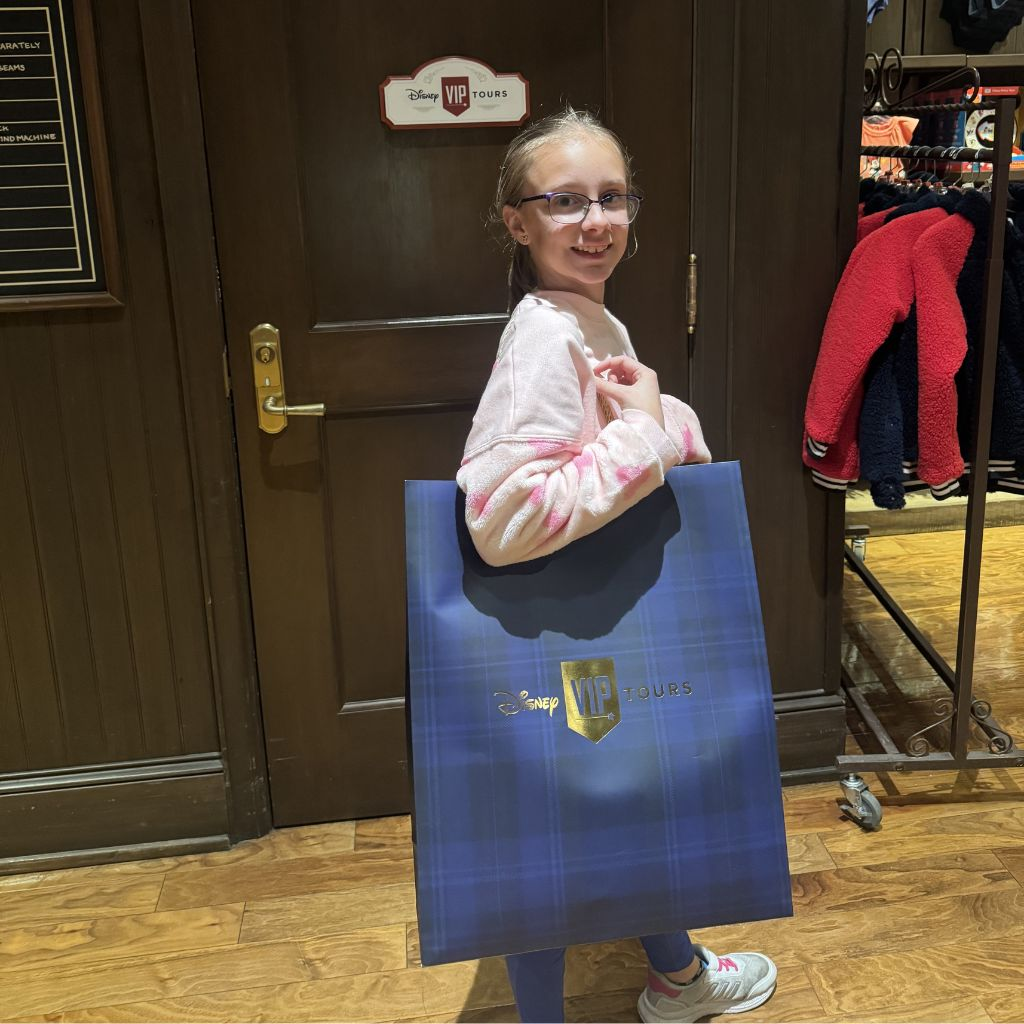 Child holding Disney VIP Tours shopping bag inside park store