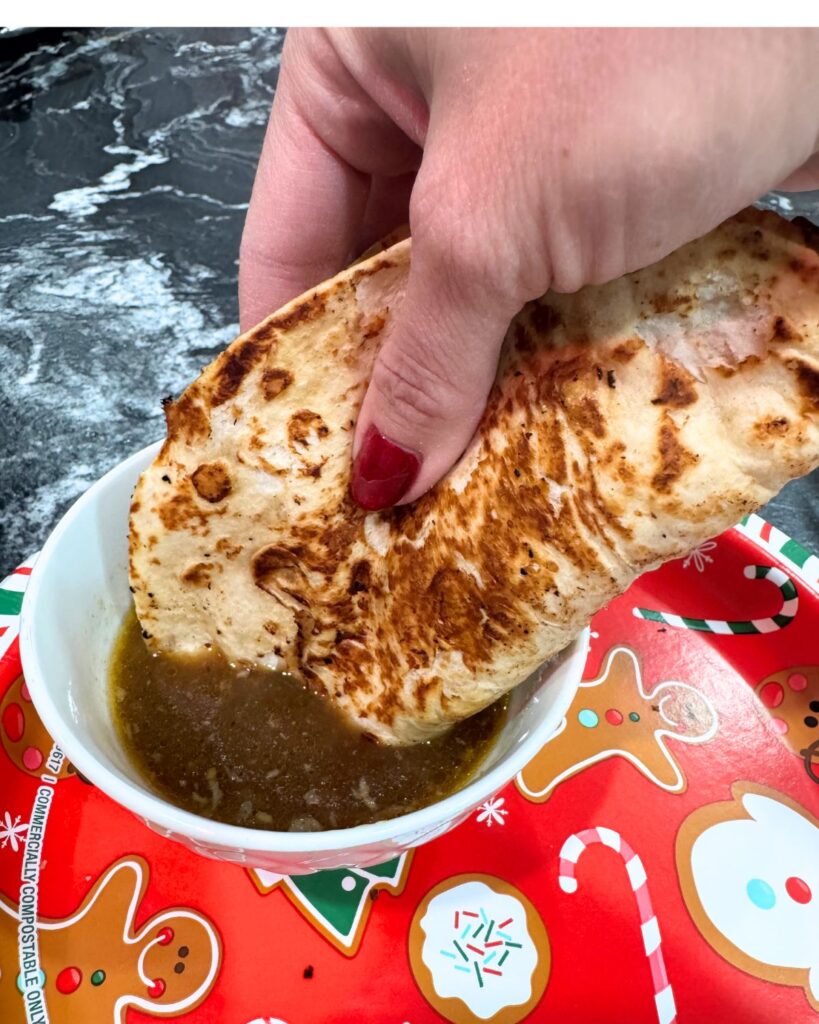 Birria quesadilla dipped into consommé broth