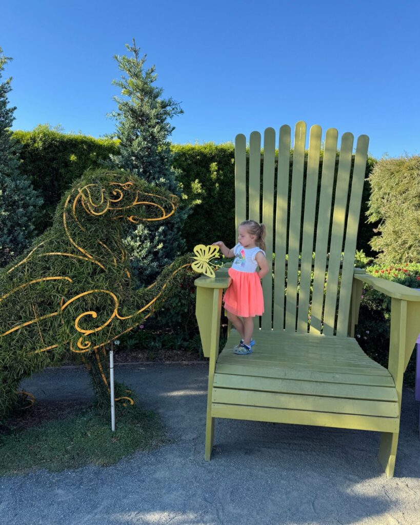 Little girl standing on a giant chair display at The Flower Fields in Carlsbad California