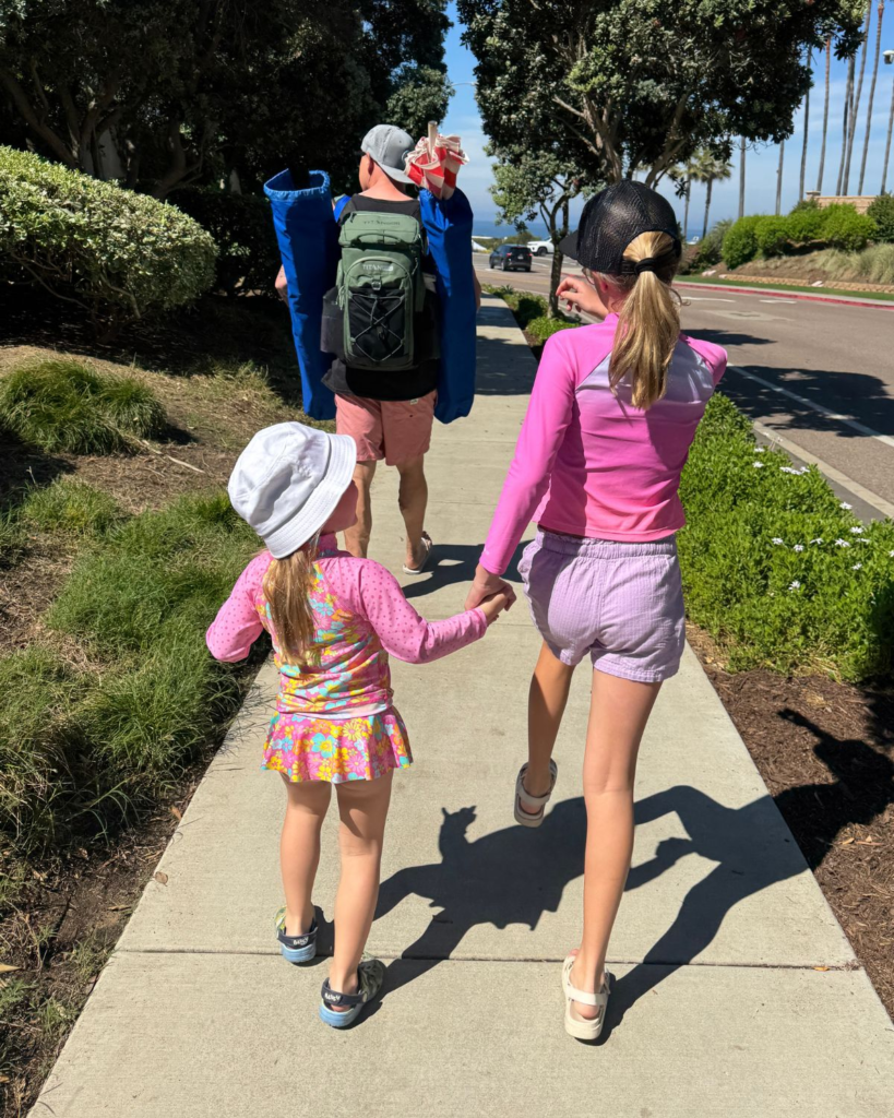 Dad and daughters walking toward the beach in Carlsbad California