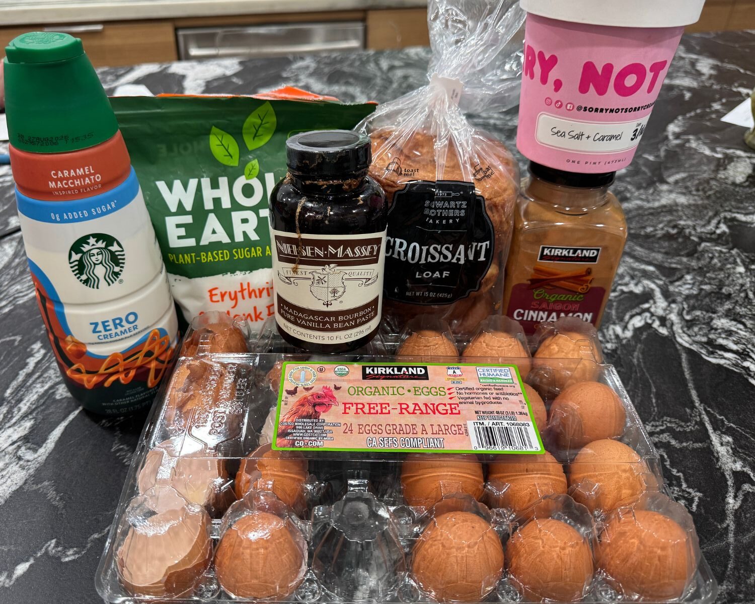 Ingredients for croissant French toast including croissant loaf bread, eggs, cinnamon, vanilla, creamer, sweetener, and ice cream