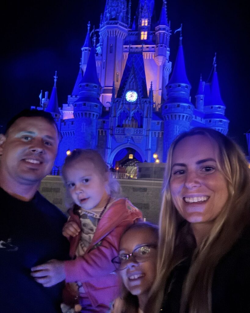 Family selfie in front of Cinderella Castle at Magic Kingdom during a Disney World vacation.
