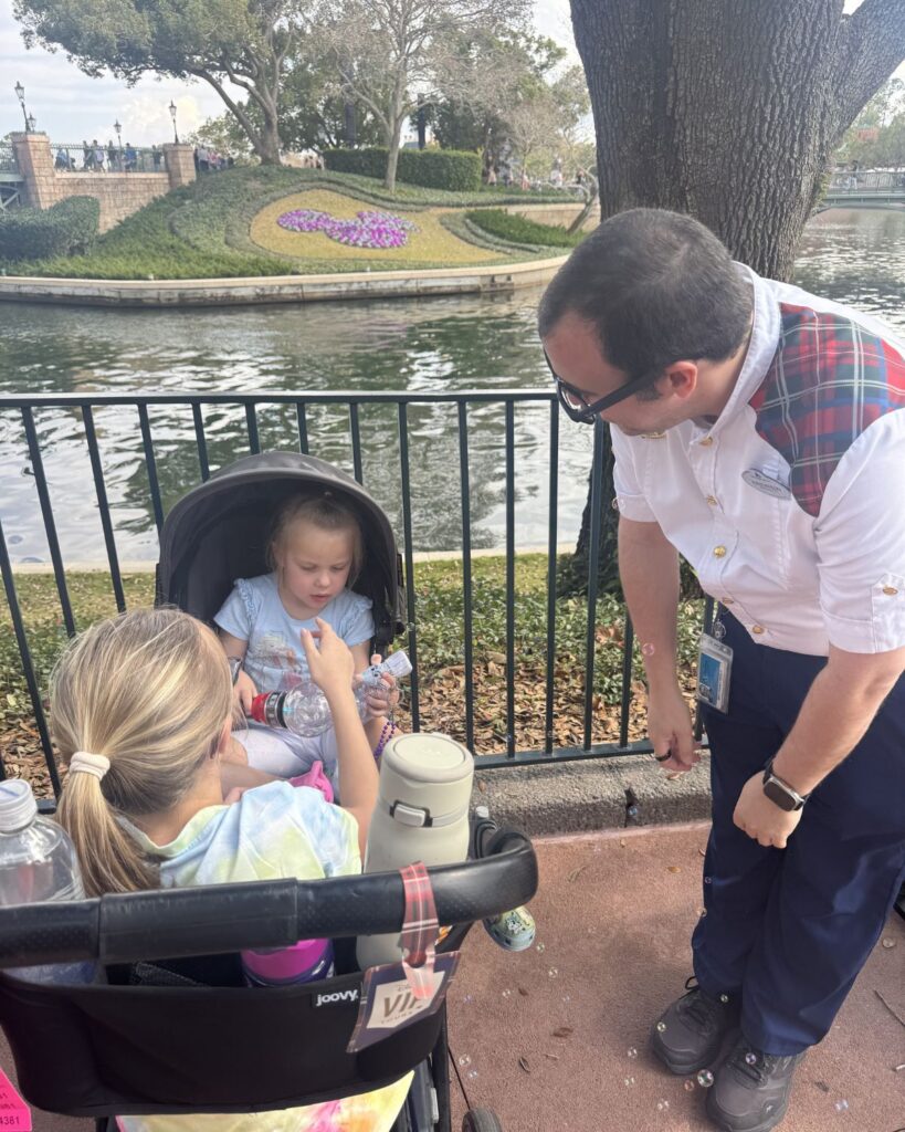 Disney VIP guide talking with kids sitting in stroller during EPCOT park day.