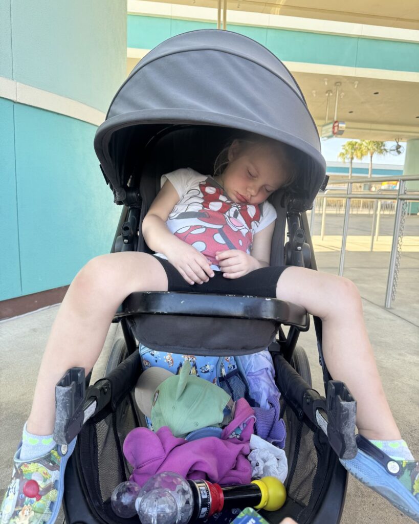 Toddler sleeping in stroller at Disney World during afternoon park nap.
