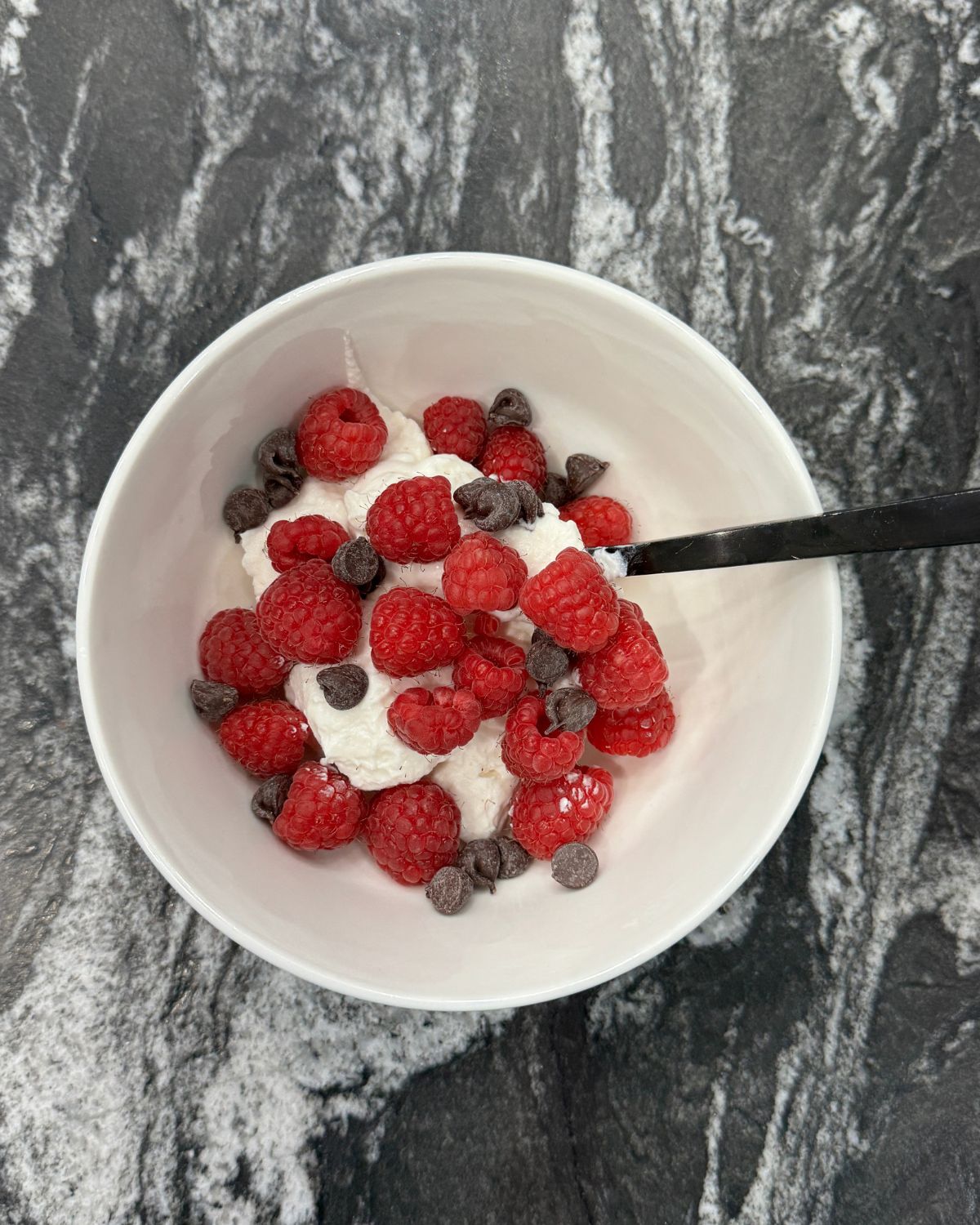 Greek yogurt bowl with fresh raspberries and chocolate chips for a quick high-protein lunch
