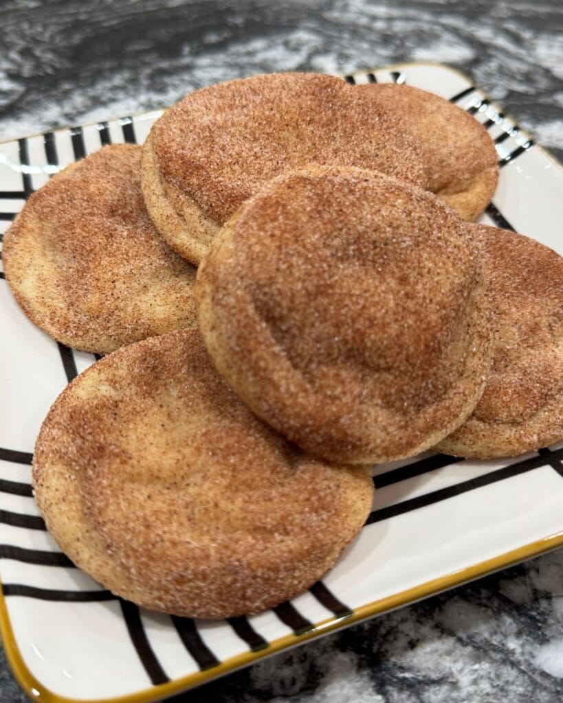 Homemade snickerdoodle cookies stacked on a striped plate