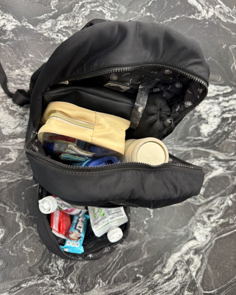 Inside a packed gym bag with pouches, water bottle, snacks, and gym bag essentials for moms