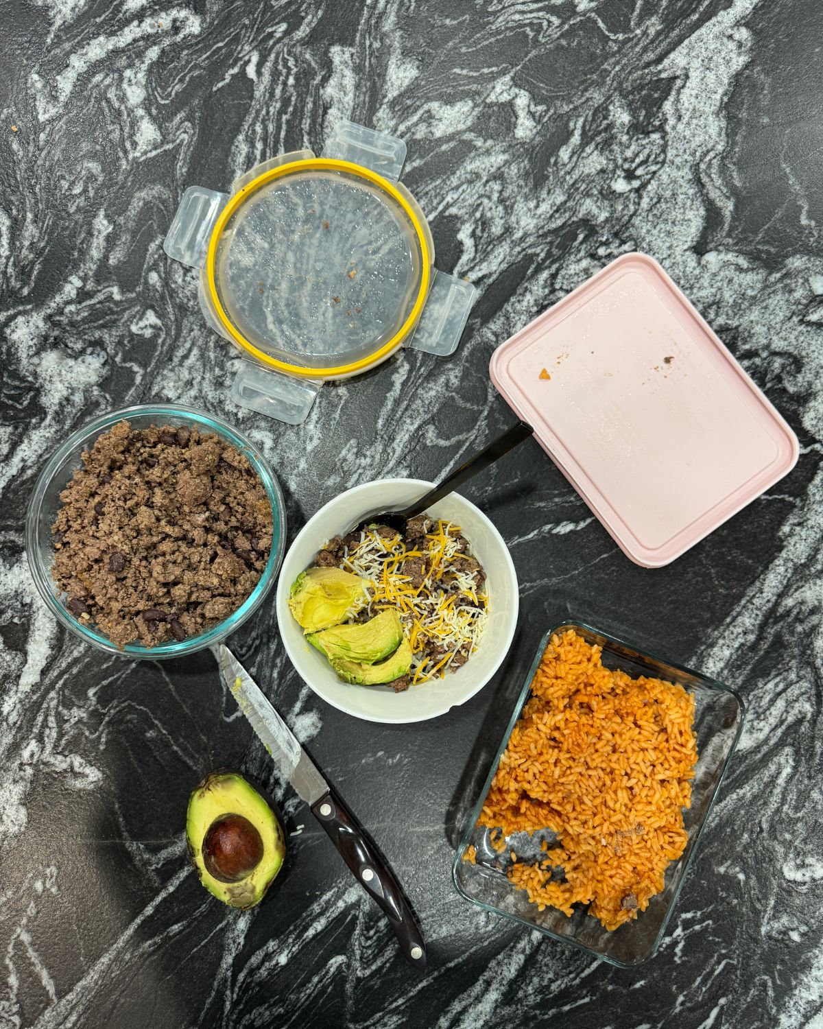 Leftover taco bowl lunch made with ground beef, Mexican rice, cheese, and avocado on a kitchen counter