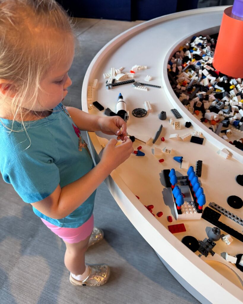Young child building with LEGO bricks at interactive play table inside LEGOLAND California