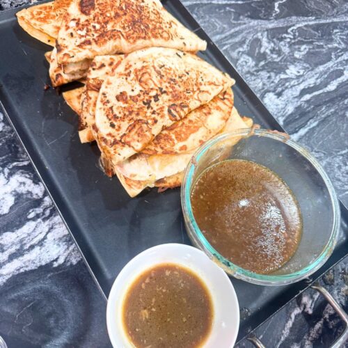 Slow cooker birria quesadillas served with consommé dipping sauce