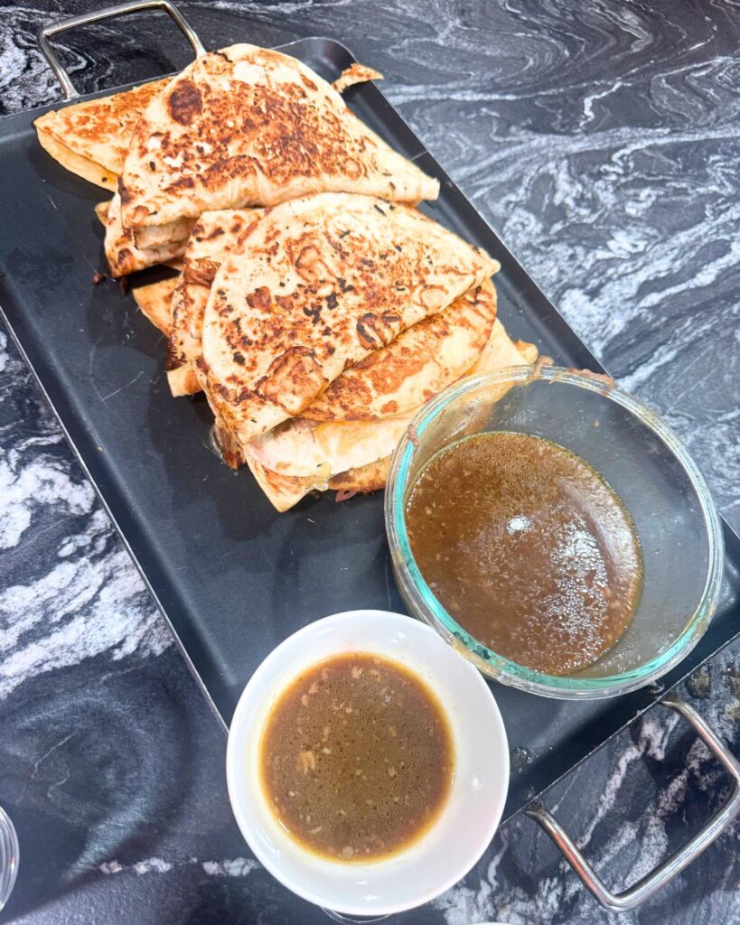 Slow cooker birria quesadillas served with consommé dipping sauce
