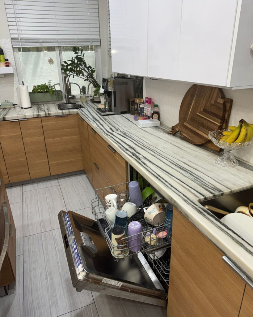 loading the dishwasher as part of a Sunday reset routine for busy moms