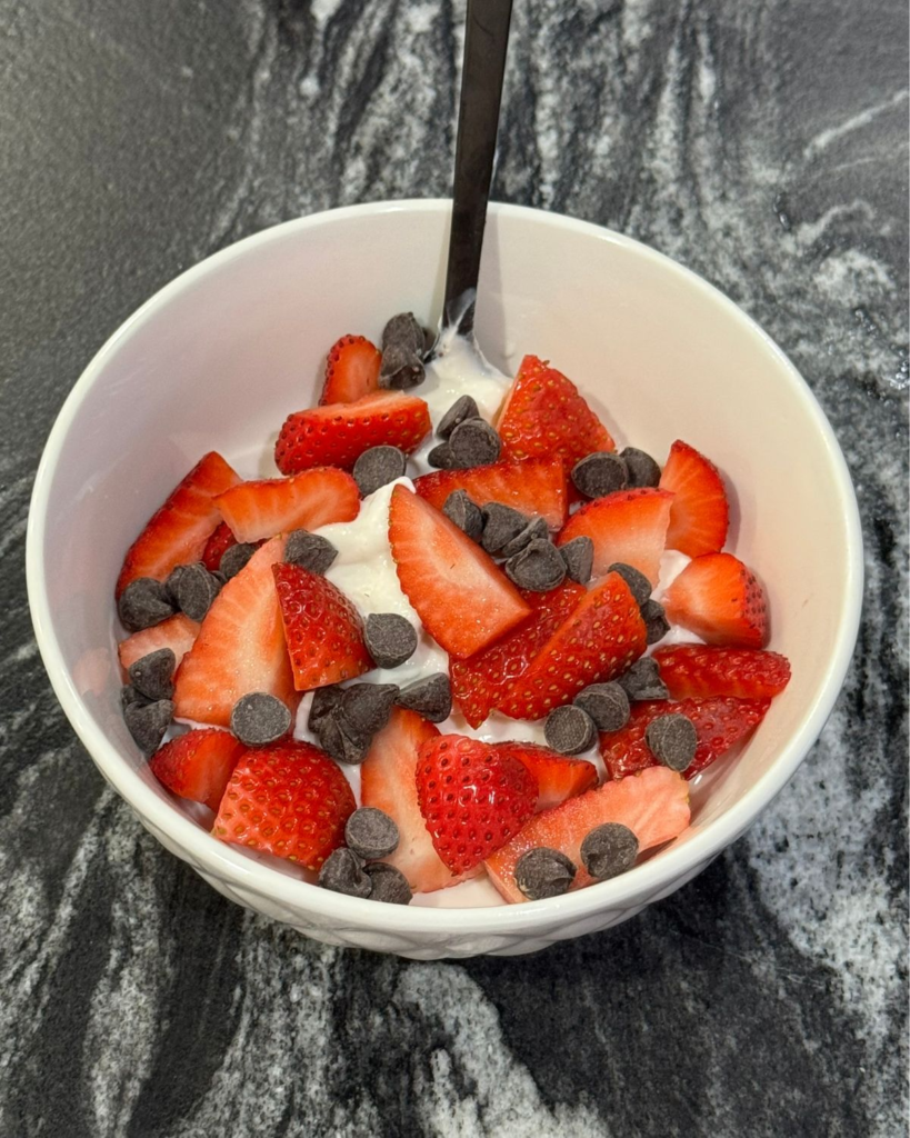 Greek yogurt topped with strawberries and chocolate chips for an easy high protein breakfast idea
