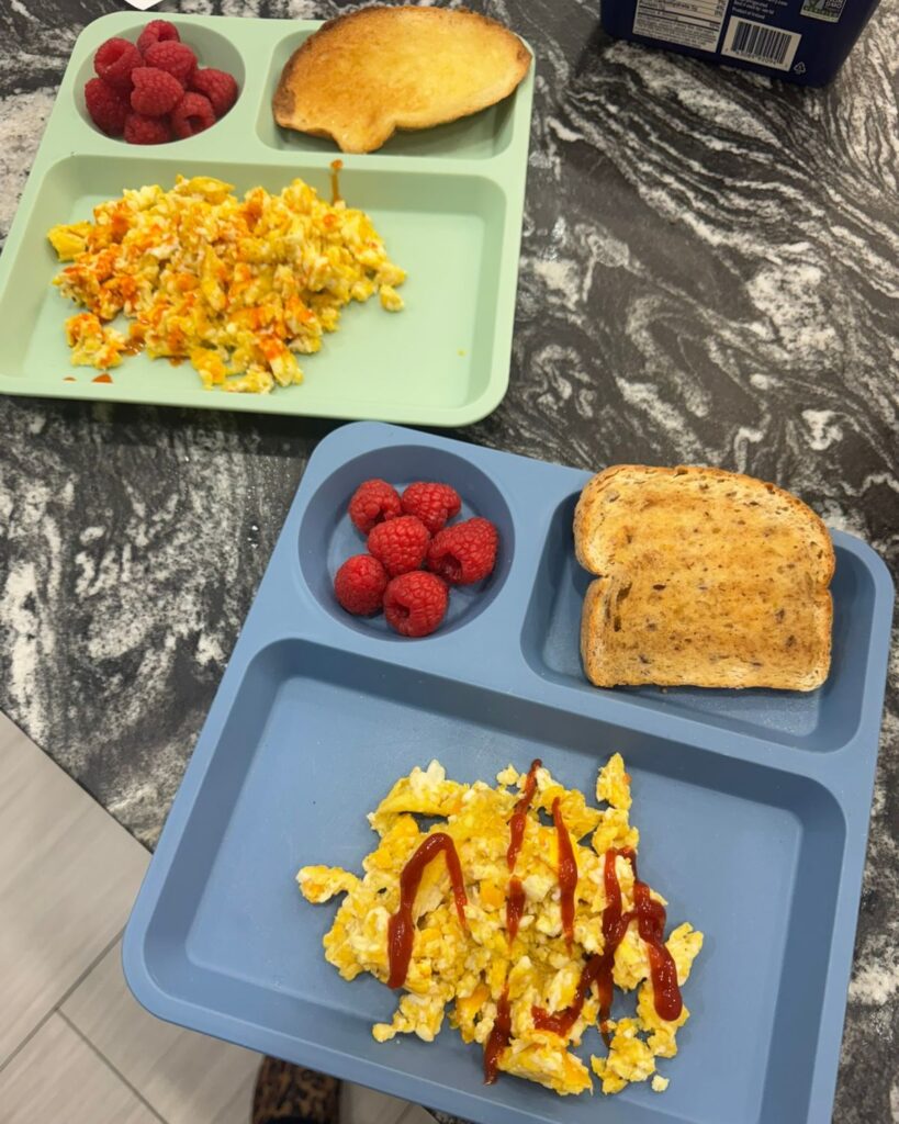 Simple kids breakfast with scrambled eggs toast and raspberries on divided plates