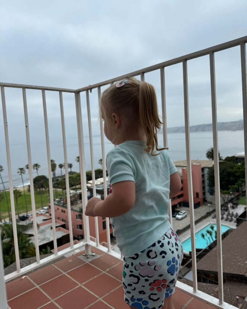 Young girl standing on a hotel balcony overlooking the ocean in La Jolla, California.