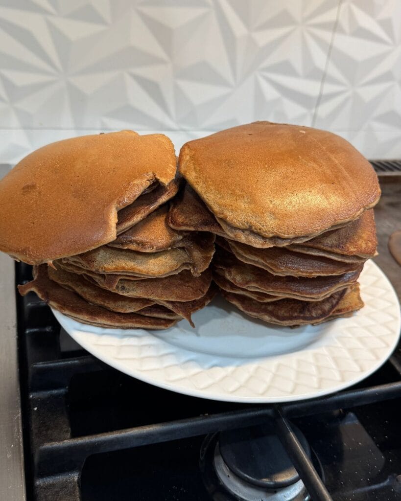 Large stack of homemade chocolate protein pancakes on a white plate.