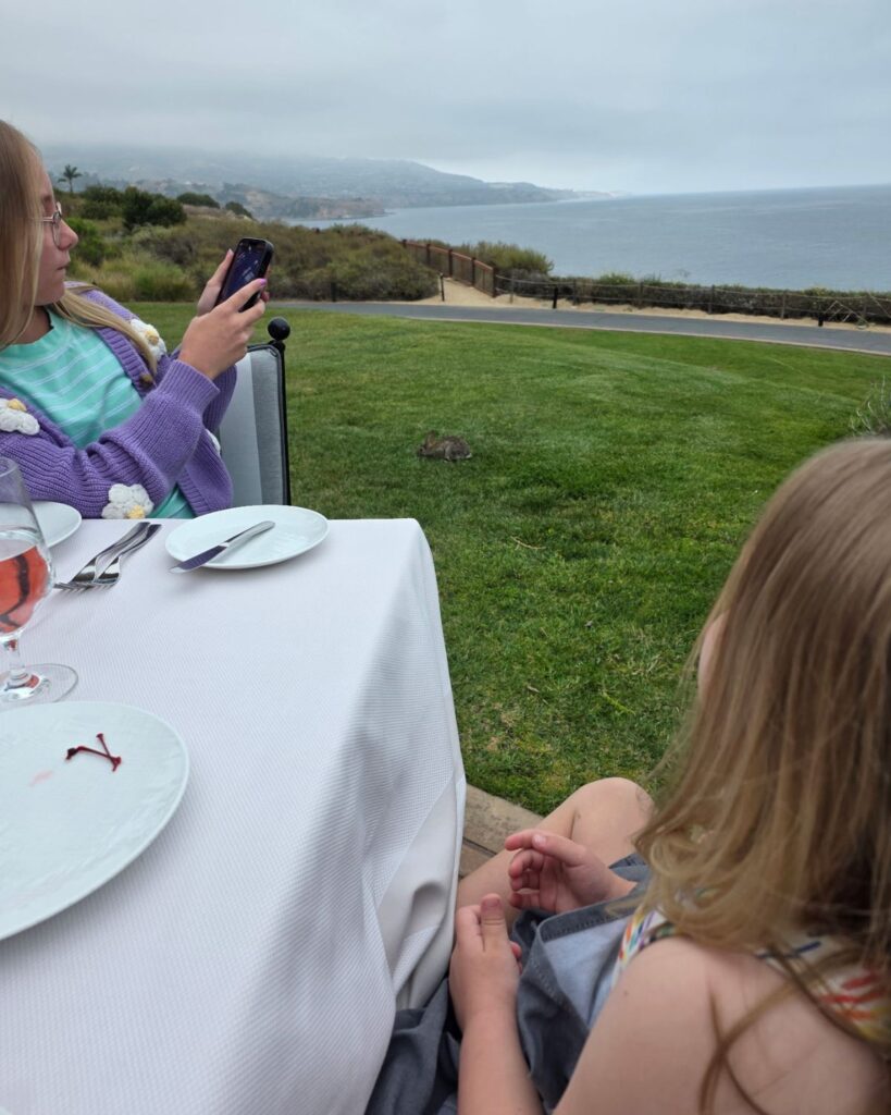 Girls sitting down for dinner at Mar'Sels with ocean view and wild bunnies at Terranea Resort