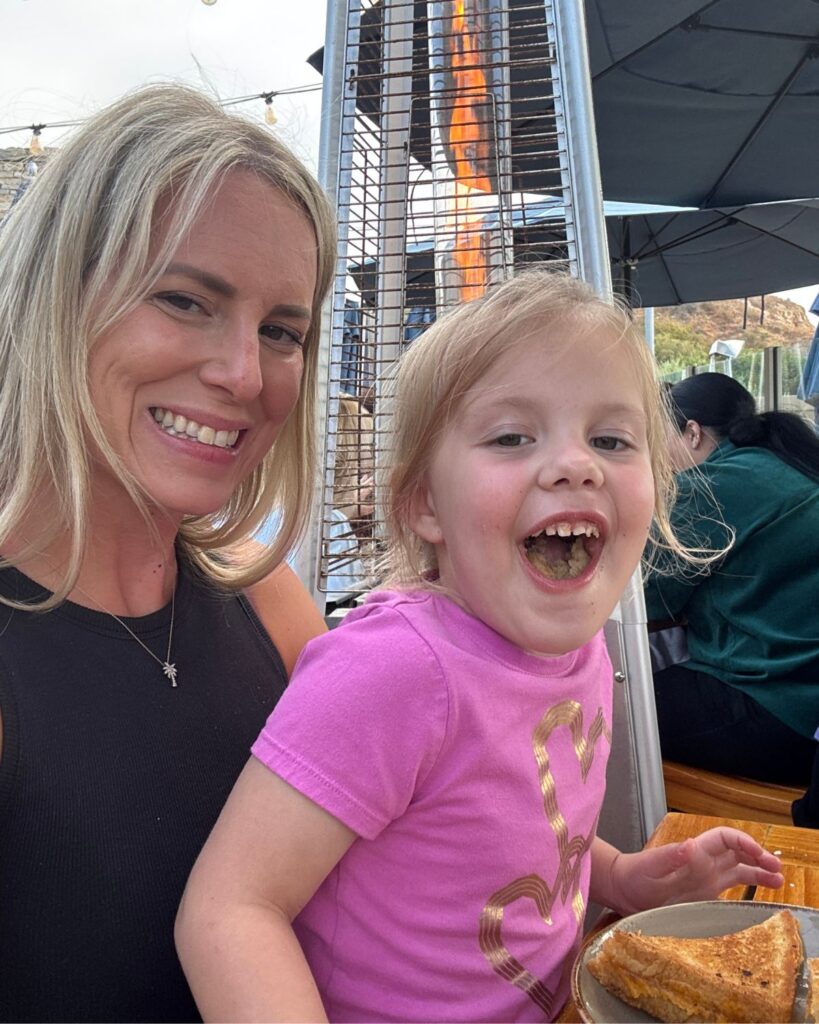 Mom with daughter eating dinner at Nelsons, with heater behind them.