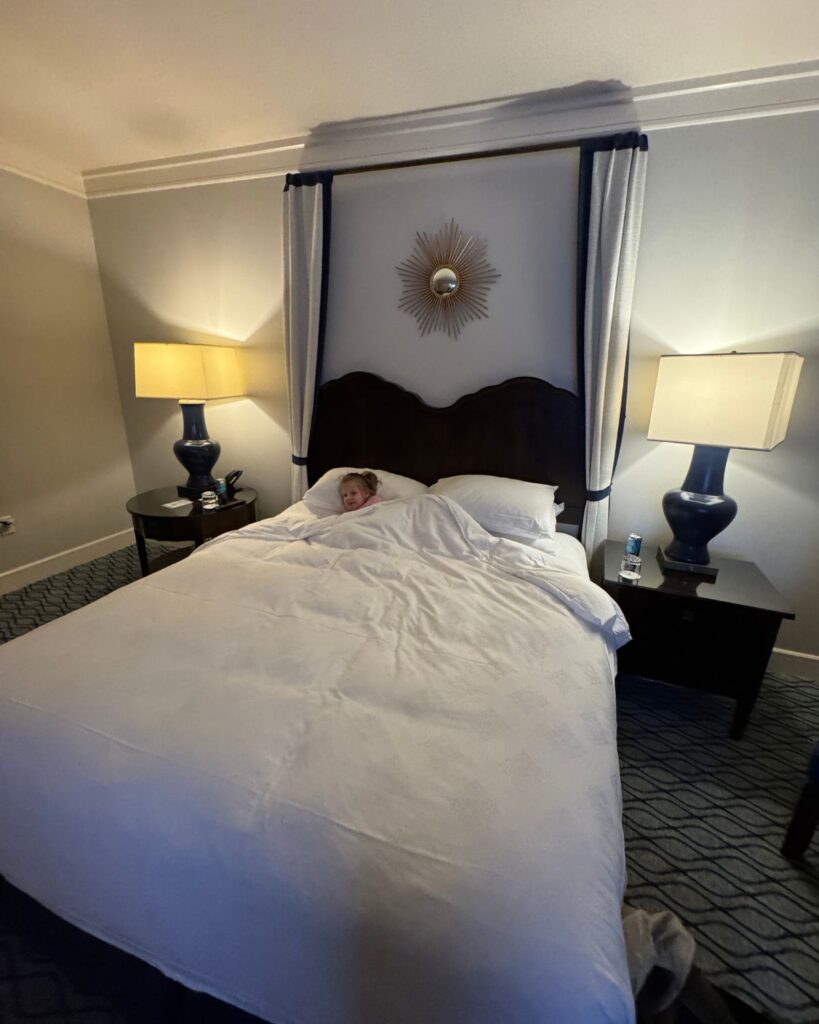 Sadie tucked into king bed in the Terranea Resort One Bedroom Hotel Suite with Premier Ocean View
