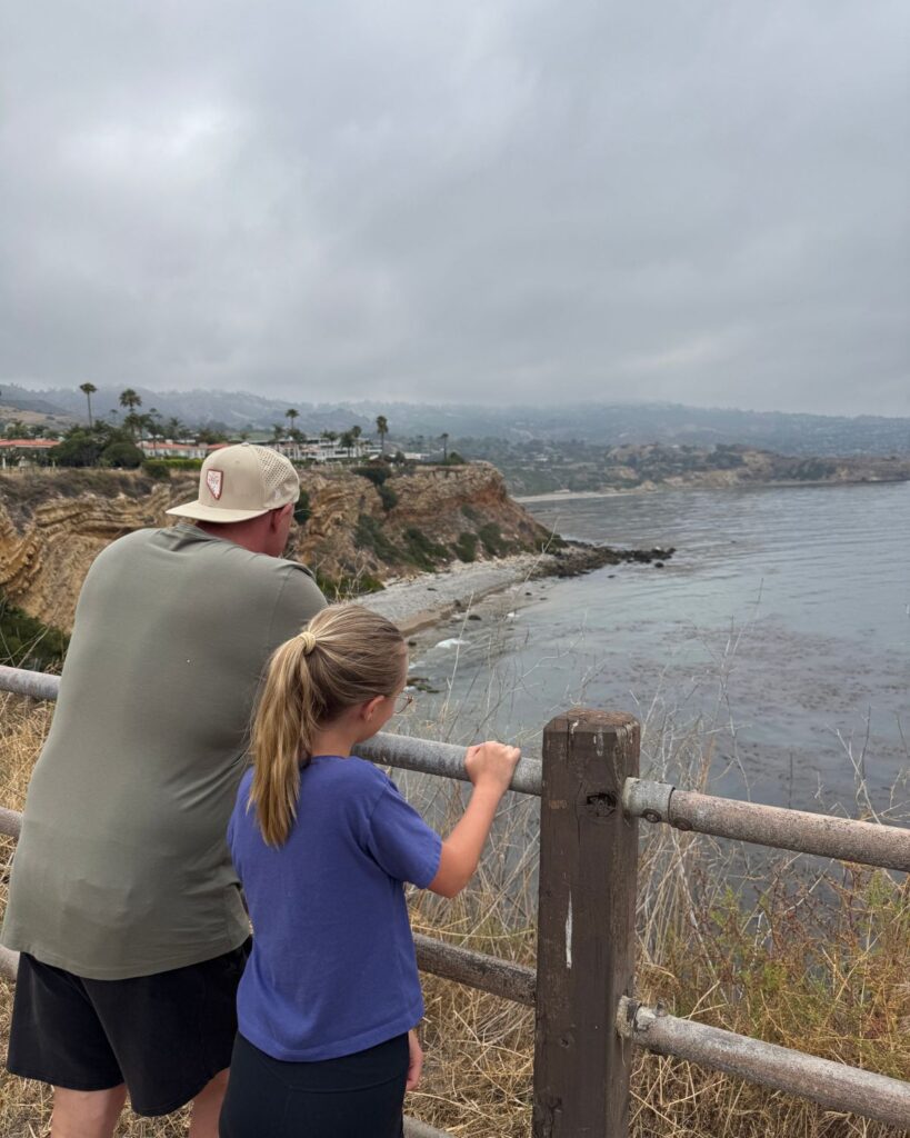 Dad with daughter overlooking views of cliff and ocean on trail around Terranea Resort
