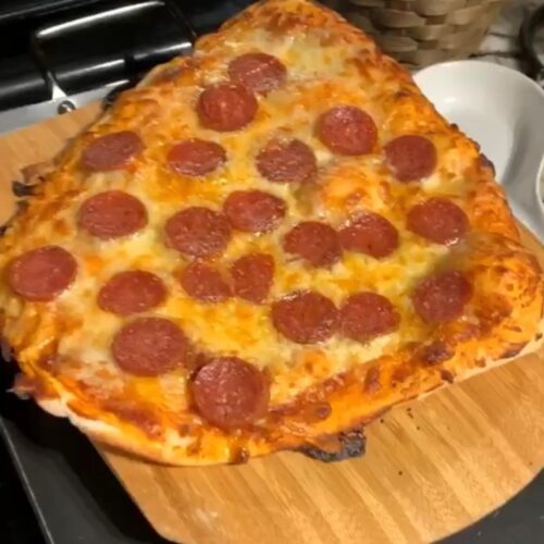 Homemade pepperoni pizza made with easy sourdough pizza dough on a wooden pizza peel.