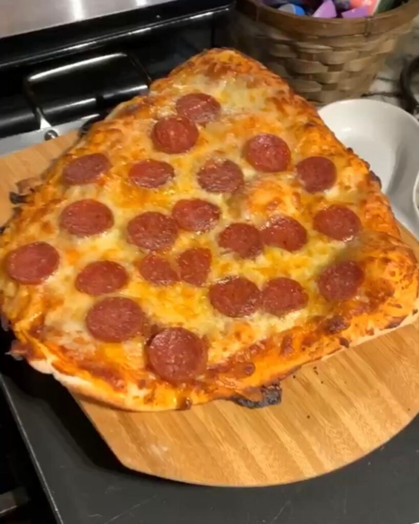Homemade pepperoni pizza made with easy sourdough pizza dough on a wooden pizza peel.