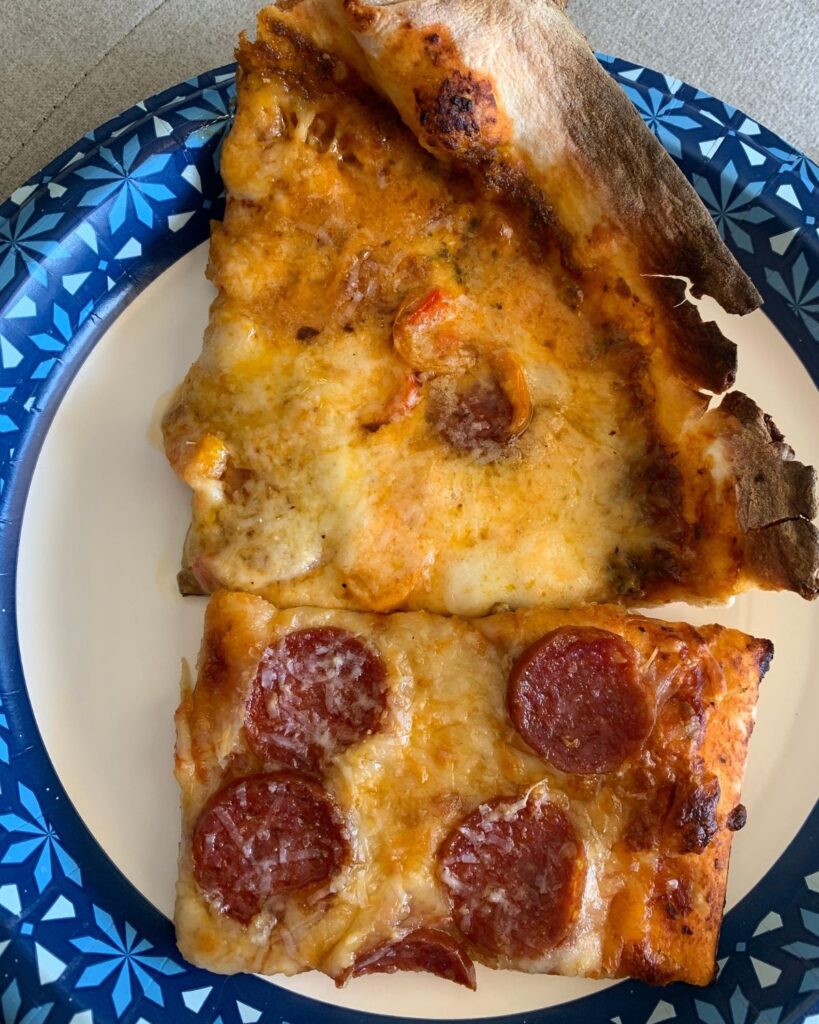 Slices of homemade sourdough pizza with pepperoni and veggie toppings served on a plate.