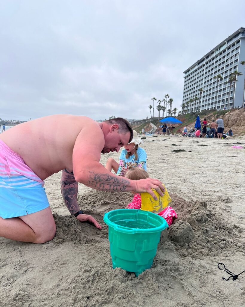 Dad helping the girls build sandcastles on Pacific Beach in front of Pacific Terrace Hotel.