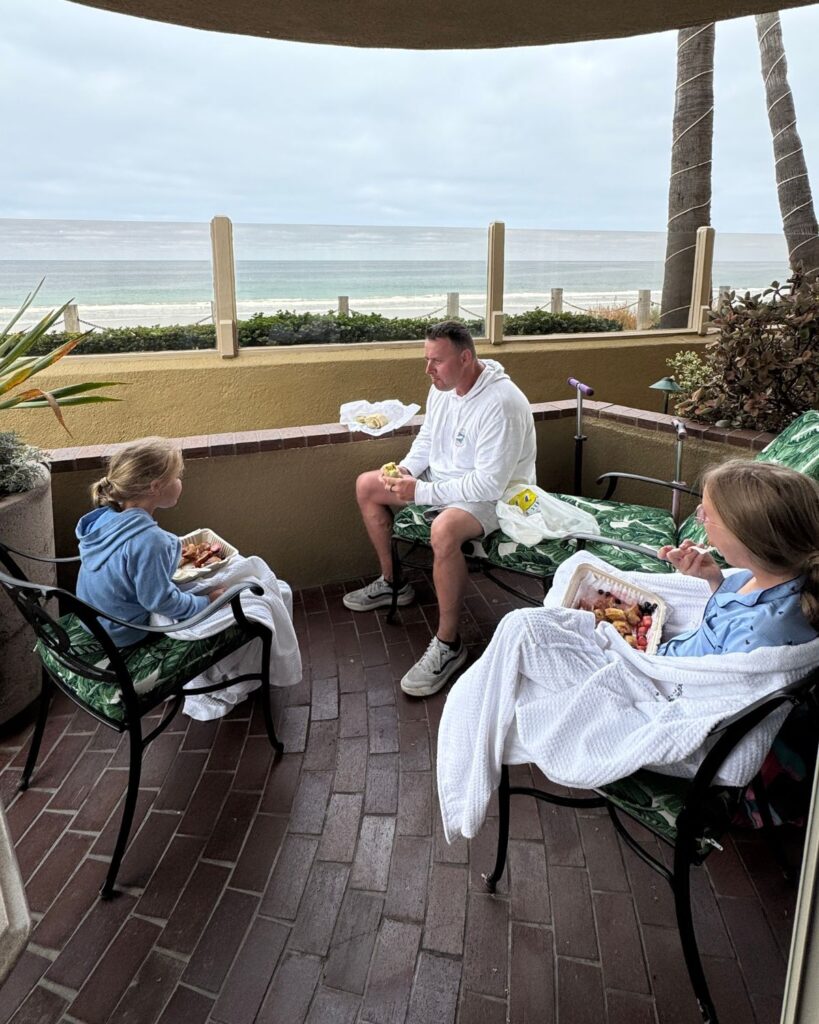 Family enjoying breakfast on the private patio outside their Family Suite overlooking the ocean.