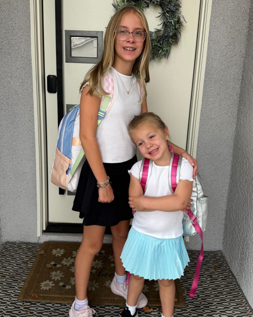 Two sisters wearing backpacks before their first day of school