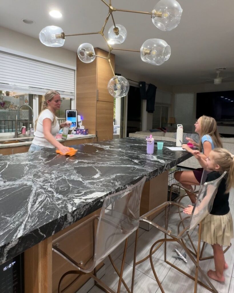 Mom doing an after-school kitchen reset while kids sit at the kitchen island