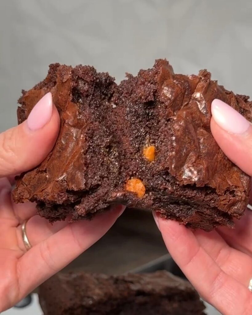 Close-up of a fudgy brownie broken in half to show the rich, chewy center and chocolate chips.