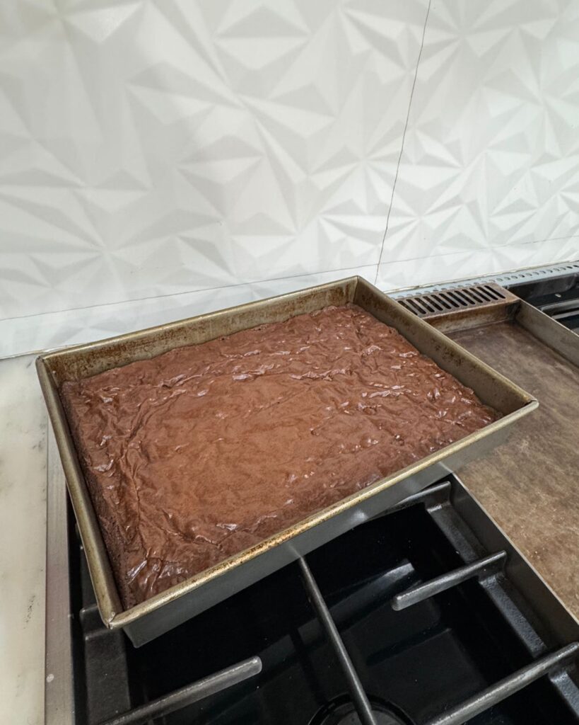 Freshly baked brownie recipe cooling in a metal 9x13 pan.