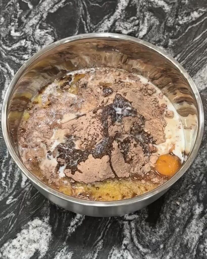 Brownie mix, butter, milk, eggs, and chocolate chips combined in a mixing bowl before stirring.