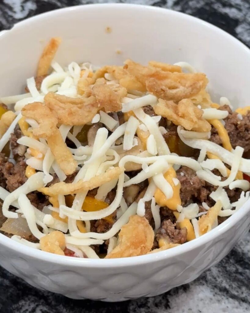 Loaded cheesesteak bowl topped with mozzarella cheese, queso and crispy fried onions