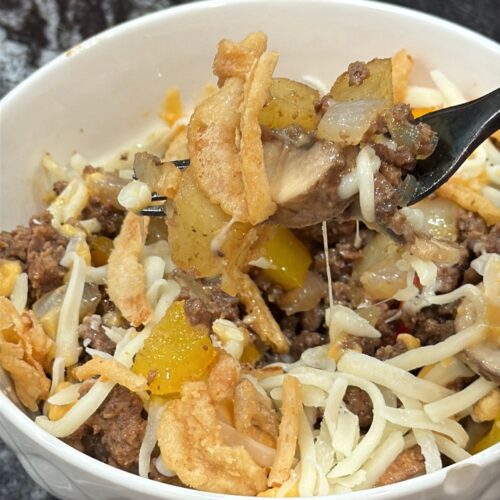 Loaded cheesesteak bowl with seasoned ground beef, roasted potatoes, peppers, onions, mushrooms and melted cheese