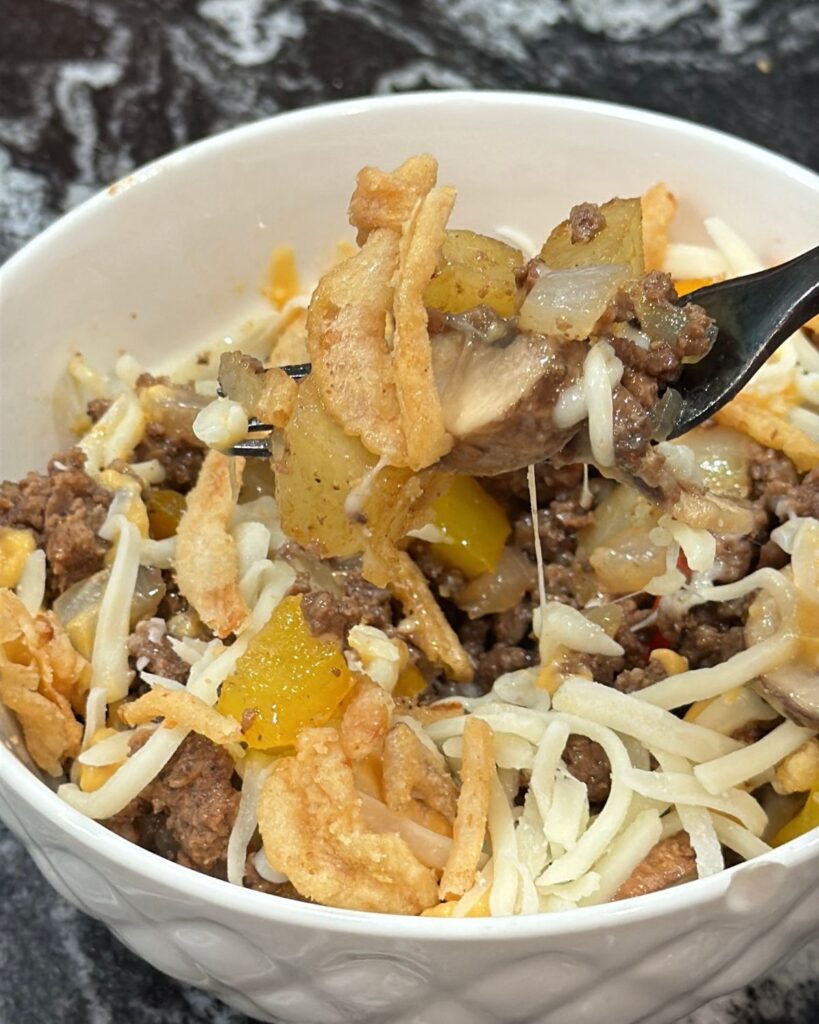 Loaded cheesesteak bowl with seasoned ground beef, roasted potatoes, peppers, onions, mushrooms and melted cheese