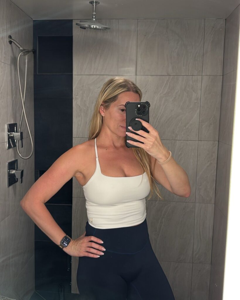 Julie showing her six-week breast lift and implant exchange results in a fitted tank top