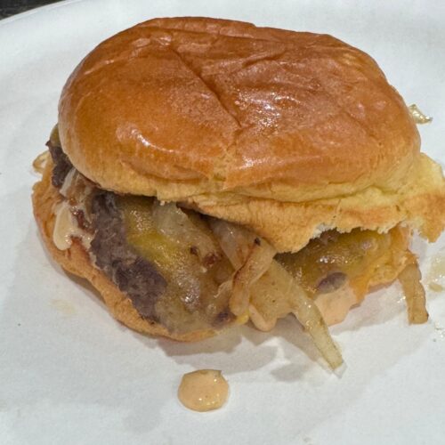Homemade smash burger topped with melted cheese and grilled onions on a brioche bun