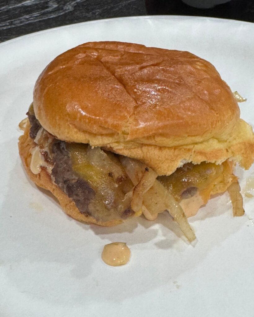 Homemade smash burger topped with melted cheese and grilled onions on a brioche bun